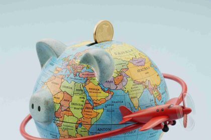 Cofrinho formato globo terrestre com avião vermelho representando hospedagem barata dicas secretas para economizar em viagens pelo mundo